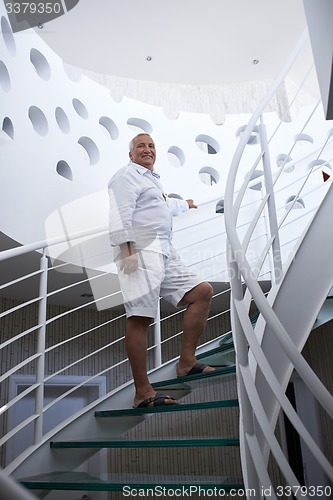 Image of senior man in front of modern home