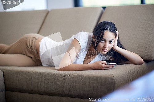 Image of young woman using cellphone at home