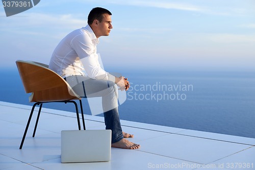 Image of relaxed young man at home on balcony