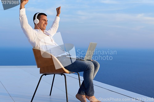 Image of relaxed young man at home on balcony