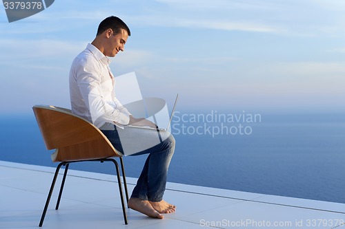 Image of relaxed young man at home on balcony