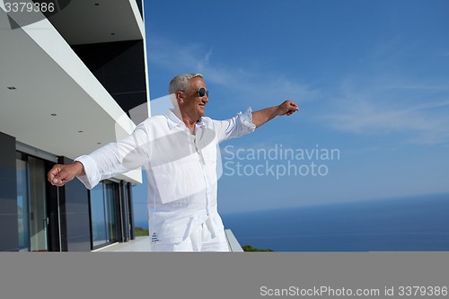 Image of senior man in front of modern home