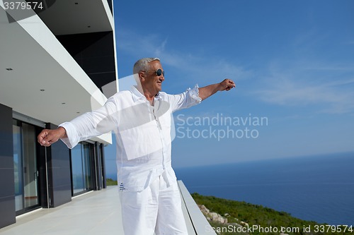 Image of senior man in front of modern home