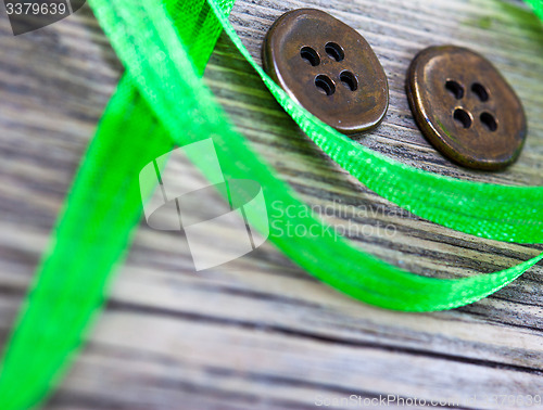 Image of still life with old green tape and two vintage buttons