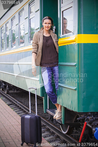 Image of beautiful adult woman on the steps of the passenger car