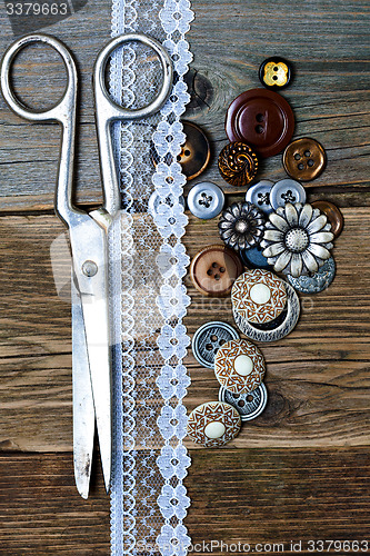 Image of aged buttons, lace and a tailor scissors