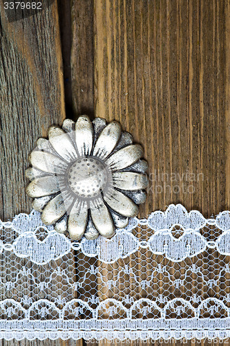 Image of vintage button and lace tape on old wooden surface