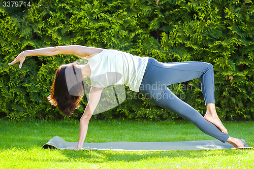 Image of beautiful adult woman doing yoga at summer park