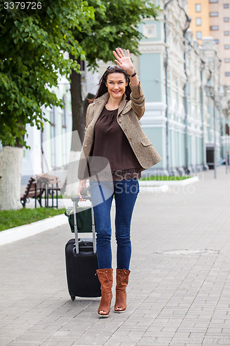 Image of adult beautiful businesswoman with a suitcase walking along the 