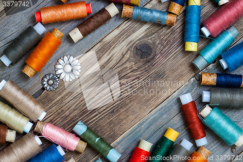 Image of two old buttons and vintage reels of varicolored thread