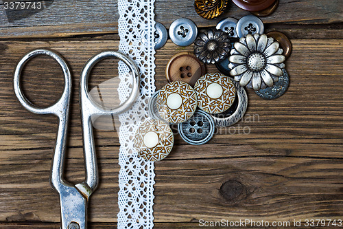 Image of several vintage buttons, lace, and a dressmaker scissors