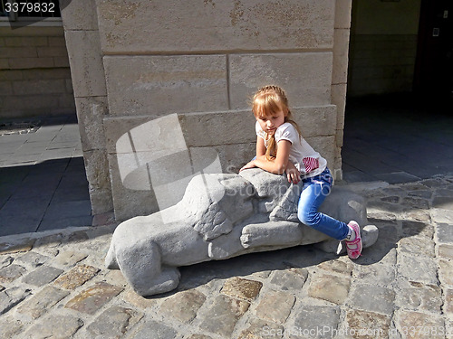 Image of Small girl sitting on the lions sculpture