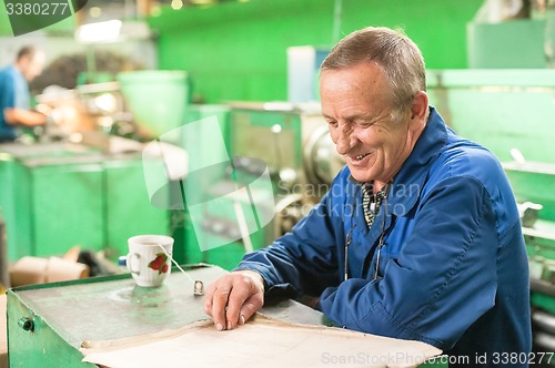 Image of Elderly smiling worker looks in drawing