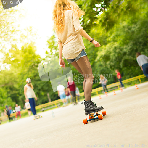 Image of Teenage girl urban long board riding.