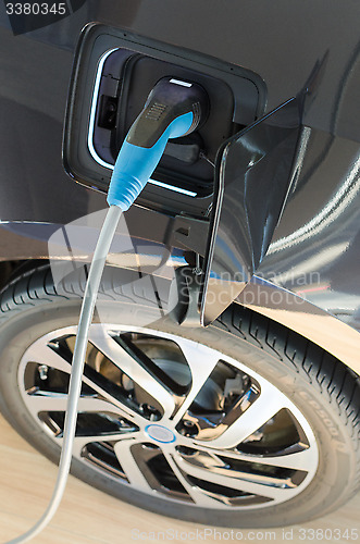 Image of Modern electric car plugged in to power supply charging station