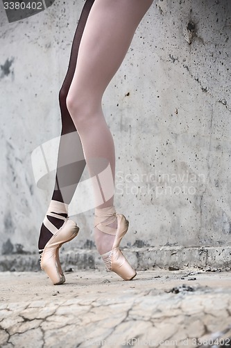 Image of Ballerina feet close-up on a background of textured concrete wal