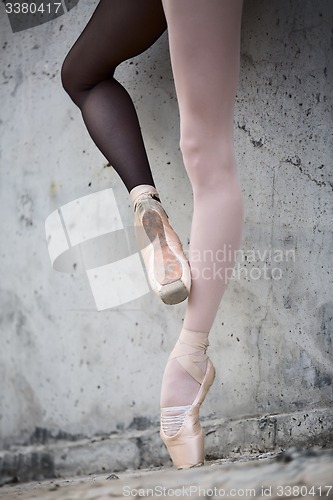 Image of Ballerina feet close-up on a background of textured concrete wal