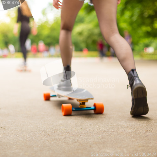 Image of Teenage girl urban long board riding.