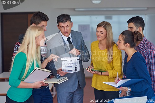 Image of group of students working with teacher on  house model