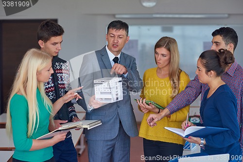 Image of group of students working with teacher on  house model