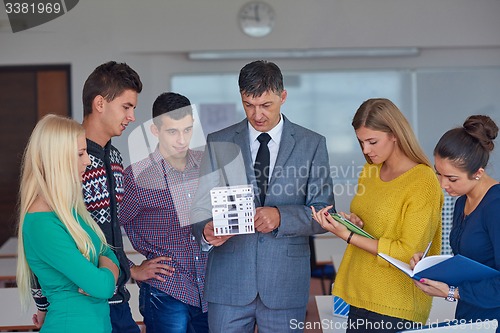 Image of group of students working with teacher on  house model