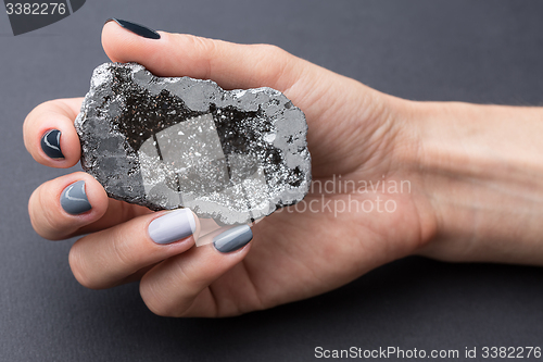 Image of Female hand with textured silver mineral