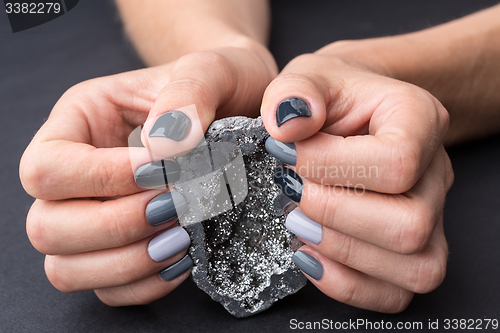 Image of Female hands with textured silver mineral