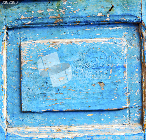 Image of stripped paint in the blue wood door and rusty nail