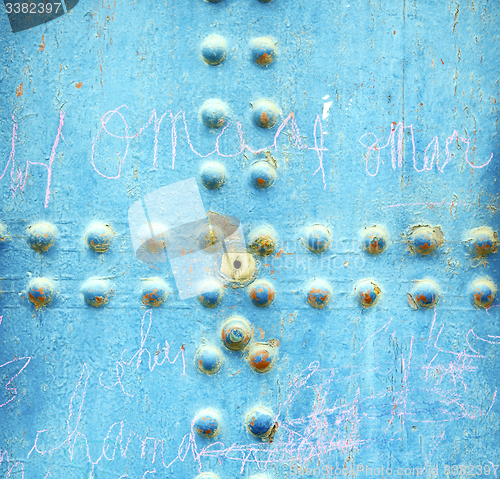 Image of dirty stripped paint in the blue wood door and rusty nail