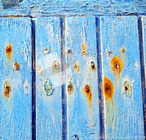 Image of stripped paint in the blue wood door and rusty nail