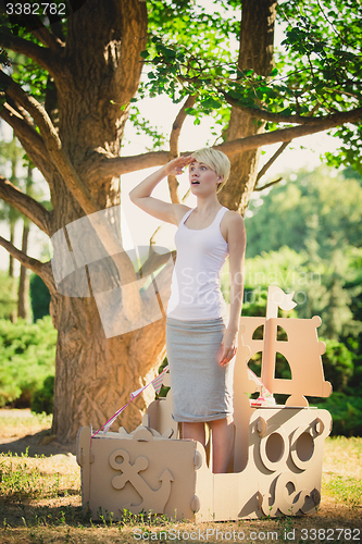 Image of Young attractive woman in a cardboard toy boat. Eco concept