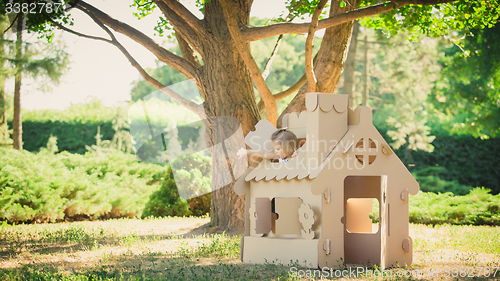 Image of girl playing in cardboard house at city park