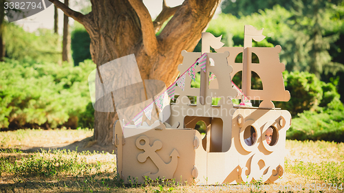 Image of Boy playing in cardboard boat at park.