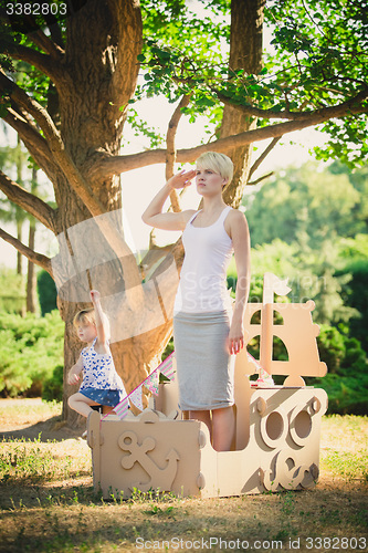 Image of Mom and child playing in a cardboard boat. Summer day.
