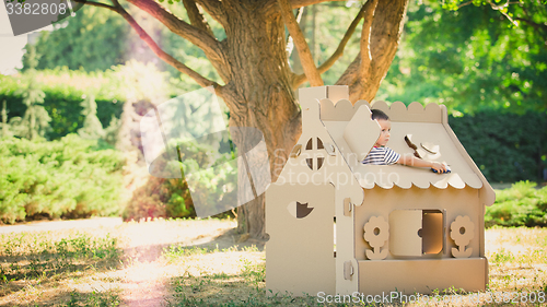 Image of boy playing in cardboard house