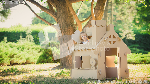 Image of girl playing in cardboard house at city park