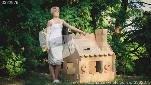 Image of attractive woman in the park with a cardboard house.