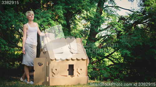 Image of attractive woman in the park with a cardboard house.