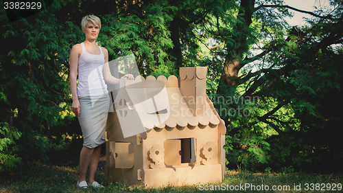 Image of attractive woman in the park with a cardboard house.