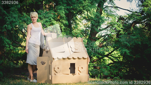 Image of attractive woman in the park with a cardboard house.