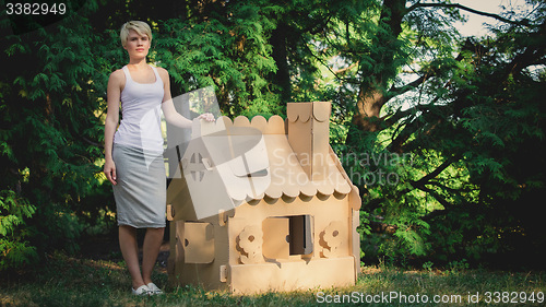 Image of attractive woman in the park with a cardboard house.