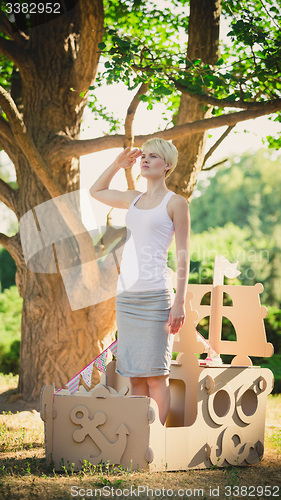 Image of Young attractive woman in a cardboard toy boat. Eco concept