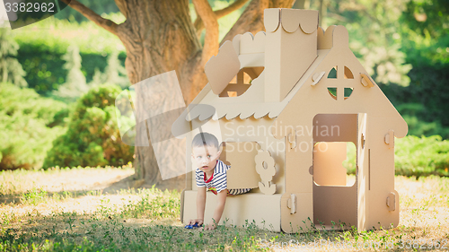 Image of boy playing in cardboard house