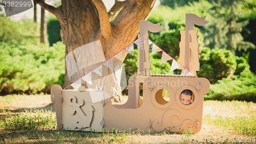 Image of Boy playing in cardboard boat at park.