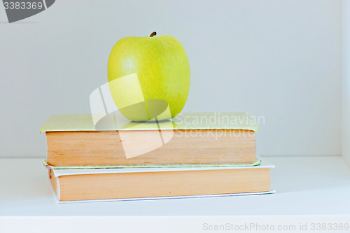 Image of A yellow apple sitting on top of a stack of books