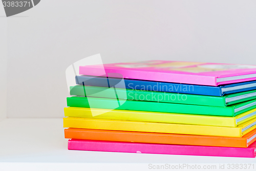 Image of Multi colored books in stack on the light-coloured bookshelf