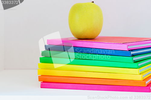 Image of A yellow apple sitting on top of a stack of school books