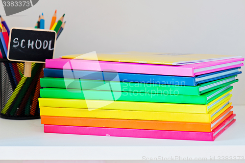 Image of Multi colored books in stack on the light-coloured bookshelf