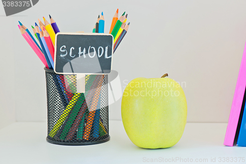 Image of Yellow apple, pencils in case and multi colored books 