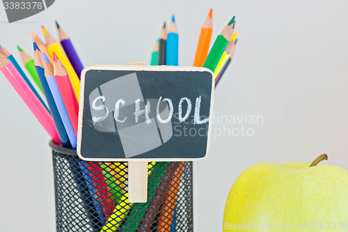 Image of Yellow apple and pencils in holder